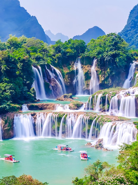 Boats on emerald waters near cascading waterfalls at Plitvice Lakes National Park.