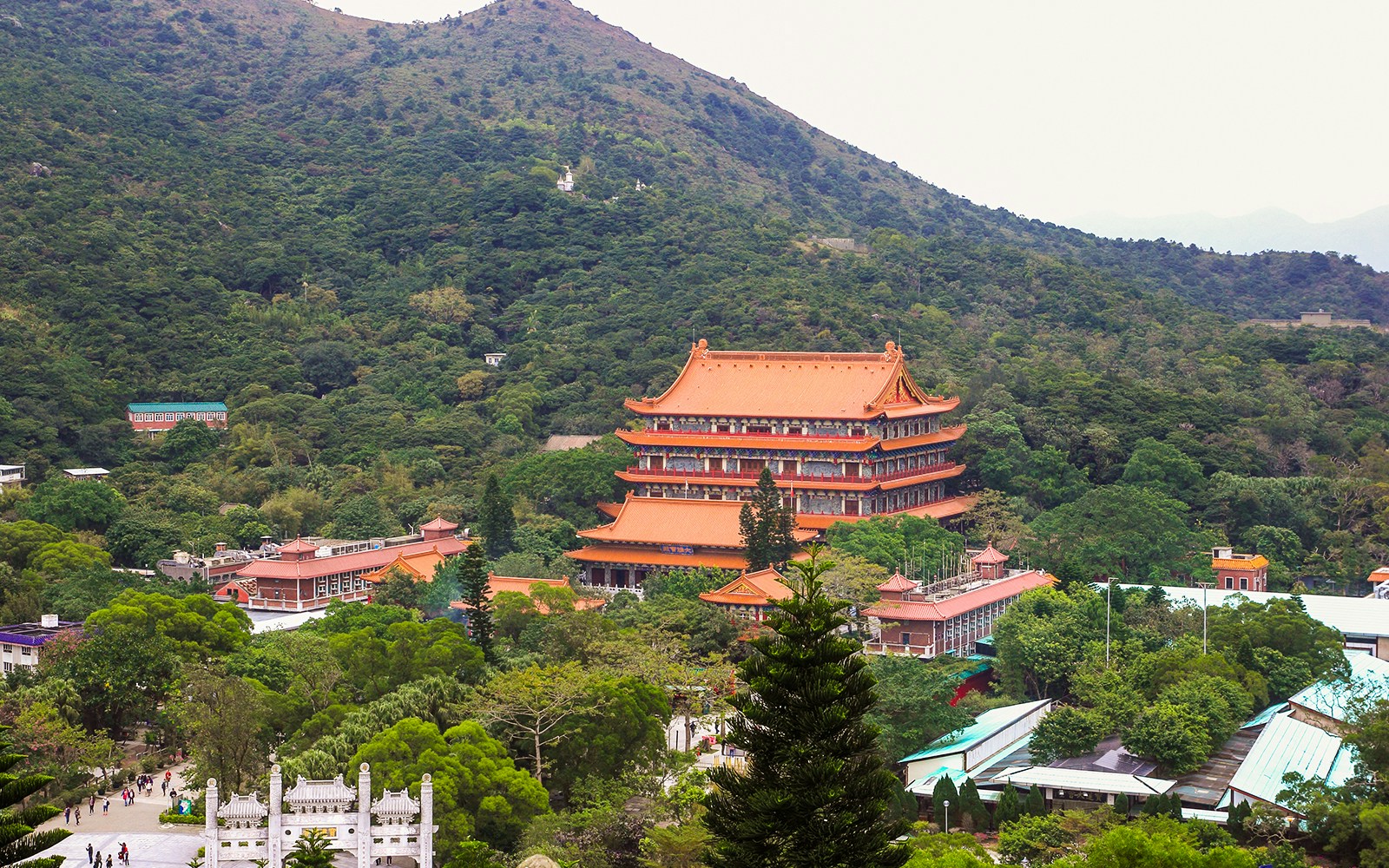 Ngong Ping Village with Po Lin Monastery surrounded by lush green hills.