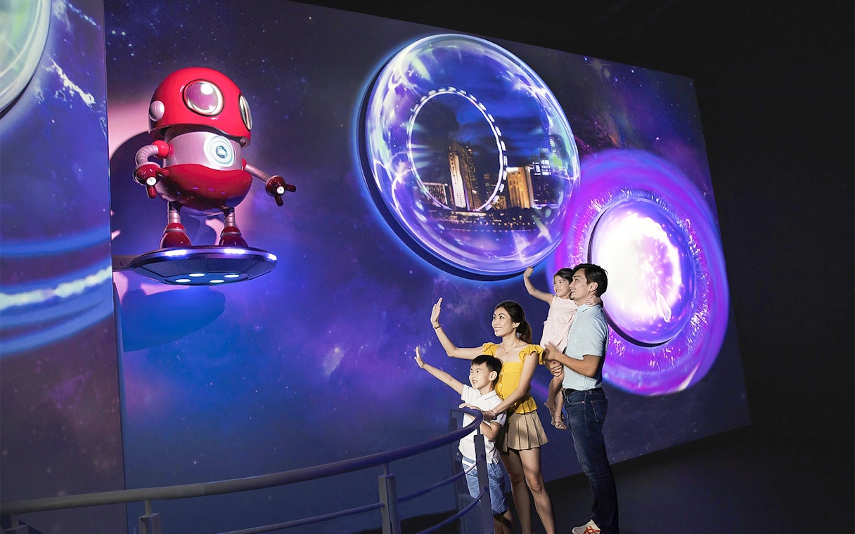 Family exploring Time Capsule exhibit at Singapore Flyer with futuristic visuals.