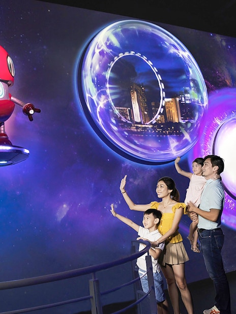 Family exploring Time Capsule exhibit at Singapore Flyer with futuristic visuals.