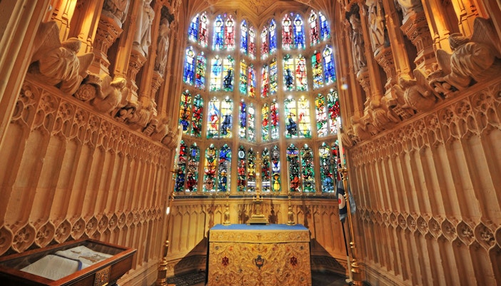Stained glass windows and ornate altar inside Westminster Abbey, London.