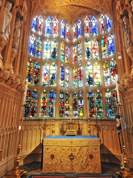 Stained glass windows and ornate altar inside Westminster Abbey, London.