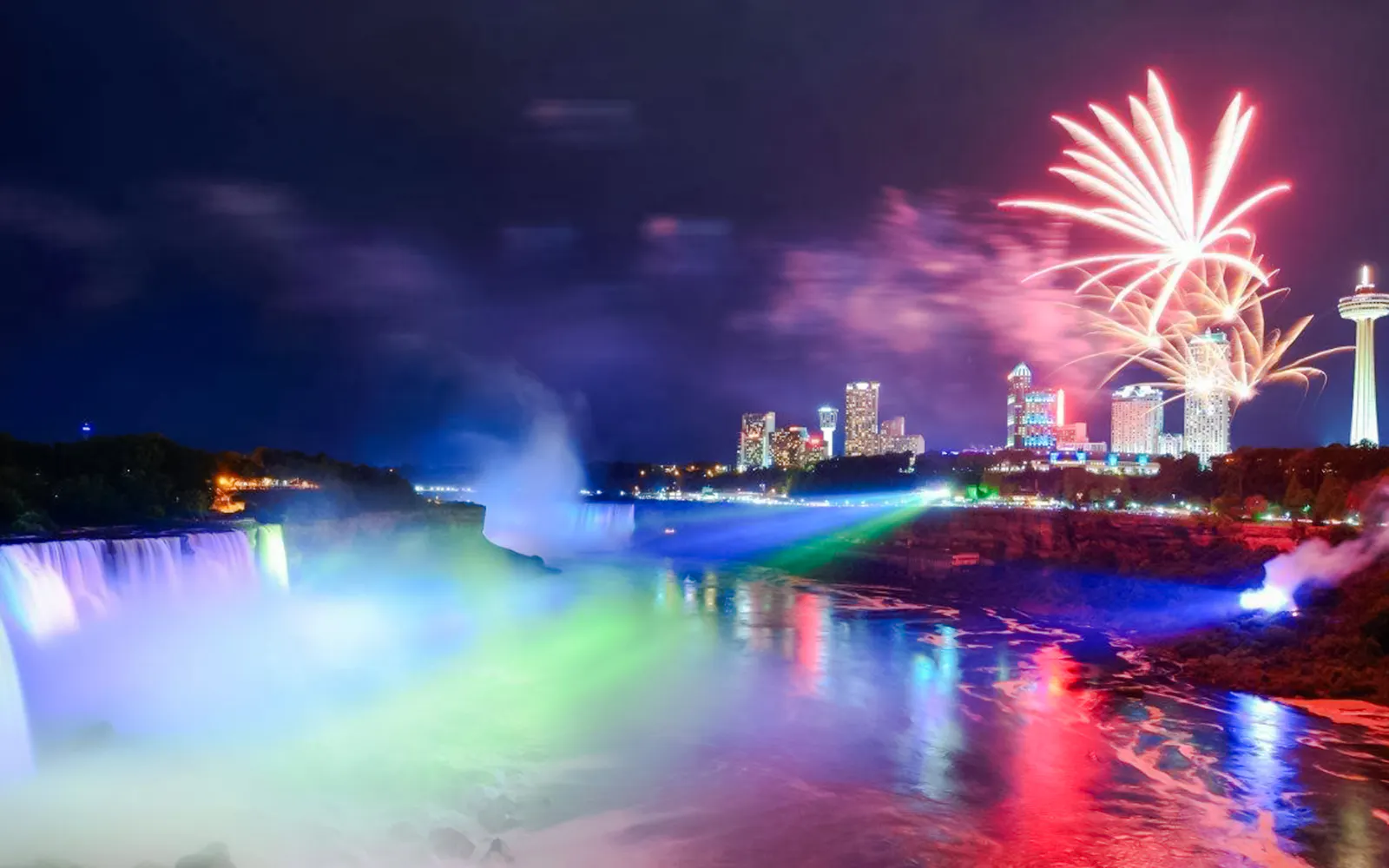 Niagara Falls USA illuminated at night with fireworks and city skyline.
