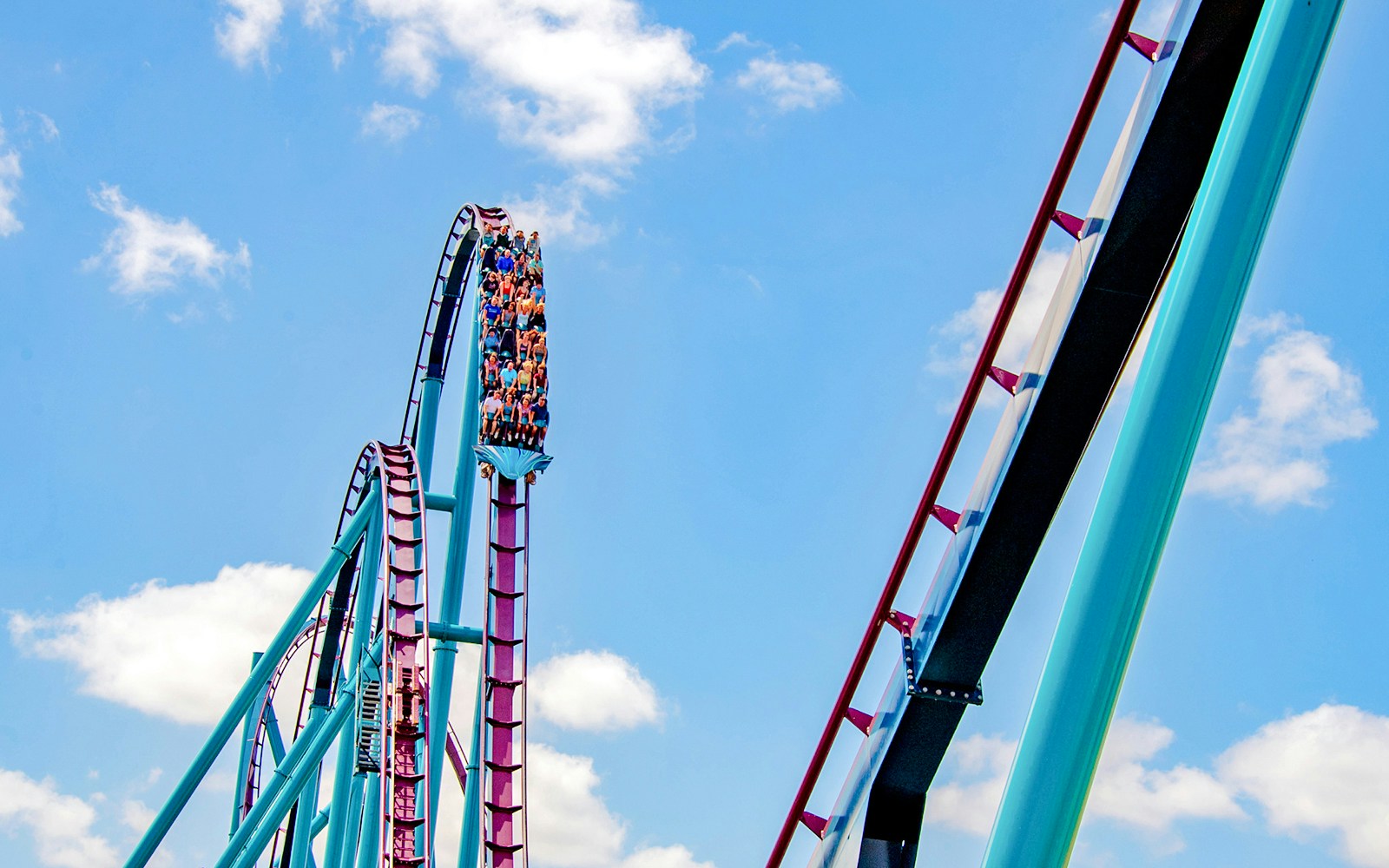 Riders on the Mako roller coaster at SeaWorld Orlando against a blue sky.