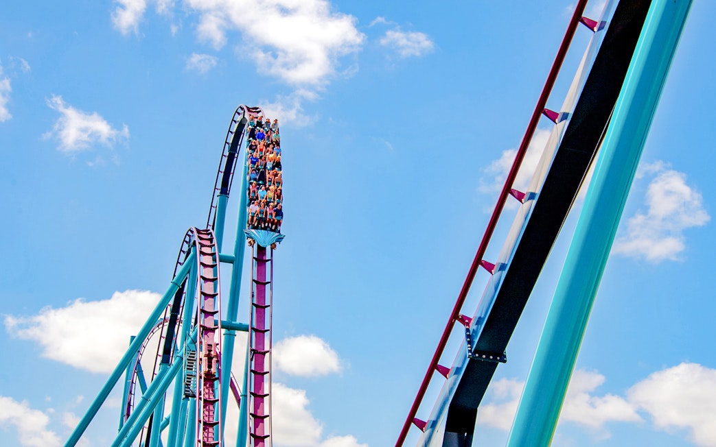 Riders on the Mako roller coaster at SeaWorld Orlando against a blue sky.