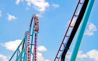 Riders on the Mako roller coaster at SeaWorld Orlando against a blue sky.