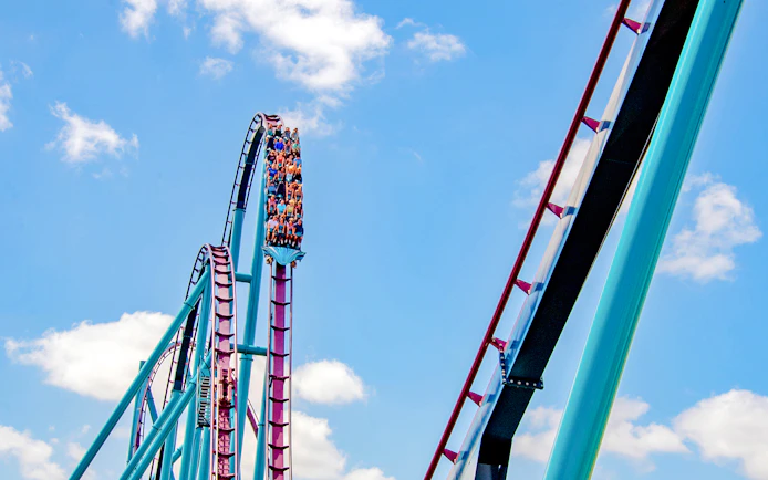 Riders on the Mako roller coaster at SeaWorld Orlando against a blue sky.