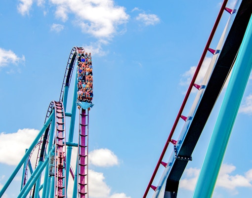 Riders on the Mako roller coaster at SeaWorld Orlando against a blue sky.