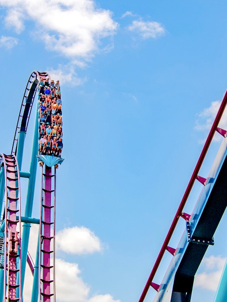 Riders on the Mako roller coaster at SeaWorld Orlando against a blue sky.