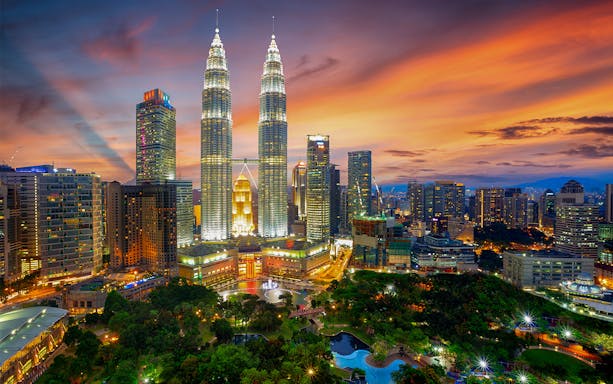 Petronas Twin Towers at sunset in Kuala Lumpur, Malaysia, with city skyline.