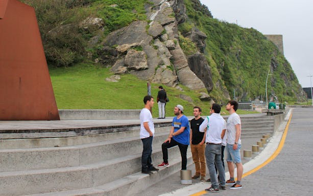 Group of tourists on a guided walking tour in San Sebastian near a modern sculpture.