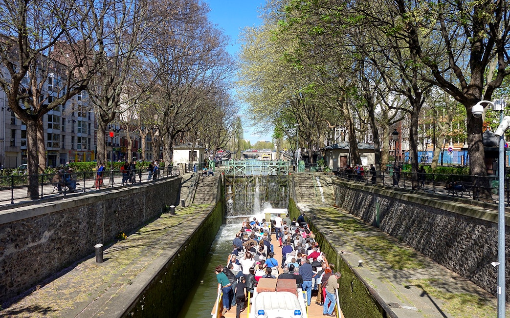 Boat tour on Canal Saint-Martin in Paris, passing through a lock with people on board.