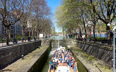 Boat tour on Canal Saint-Martin in Paris, passing through a lock with people on board.