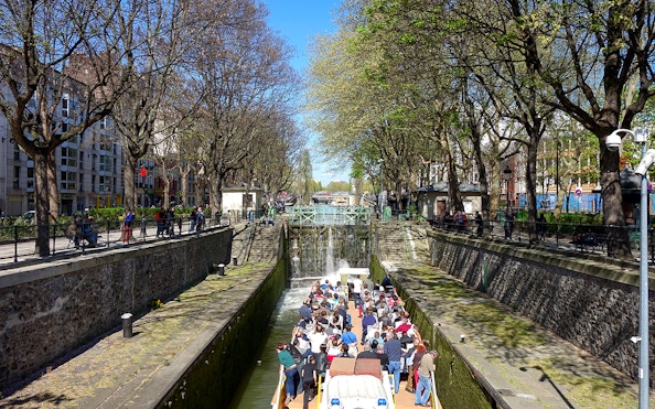 Boat tour on Canal Saint-Martin in Paris, passing through a lock with people on board.