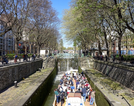 Boat tour on Canal Saint-Martin in Paris, passing through a lock with people on board.