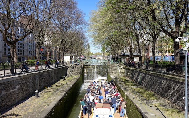 Boat tour on Canal Saint-Martin in Paris, passing through a lock with people on board.