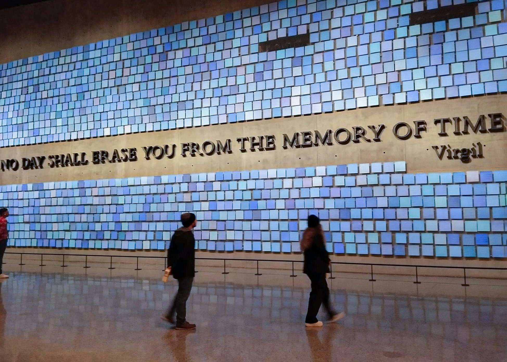 Visitors at the 9/11 Memorial viewing the "No Day Shall Erase You" wall.