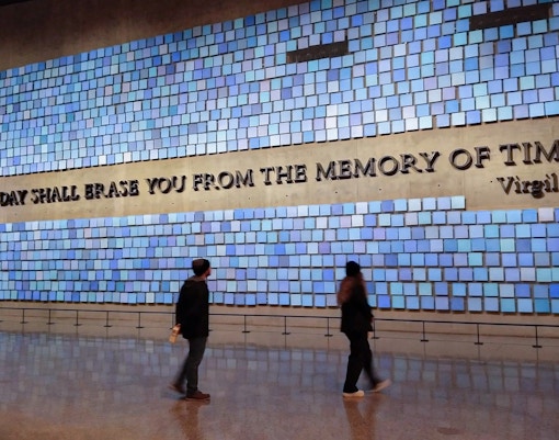 Visitors at the 9/11 Memorial in New York City, viewing the reflecting pools and engraved names.