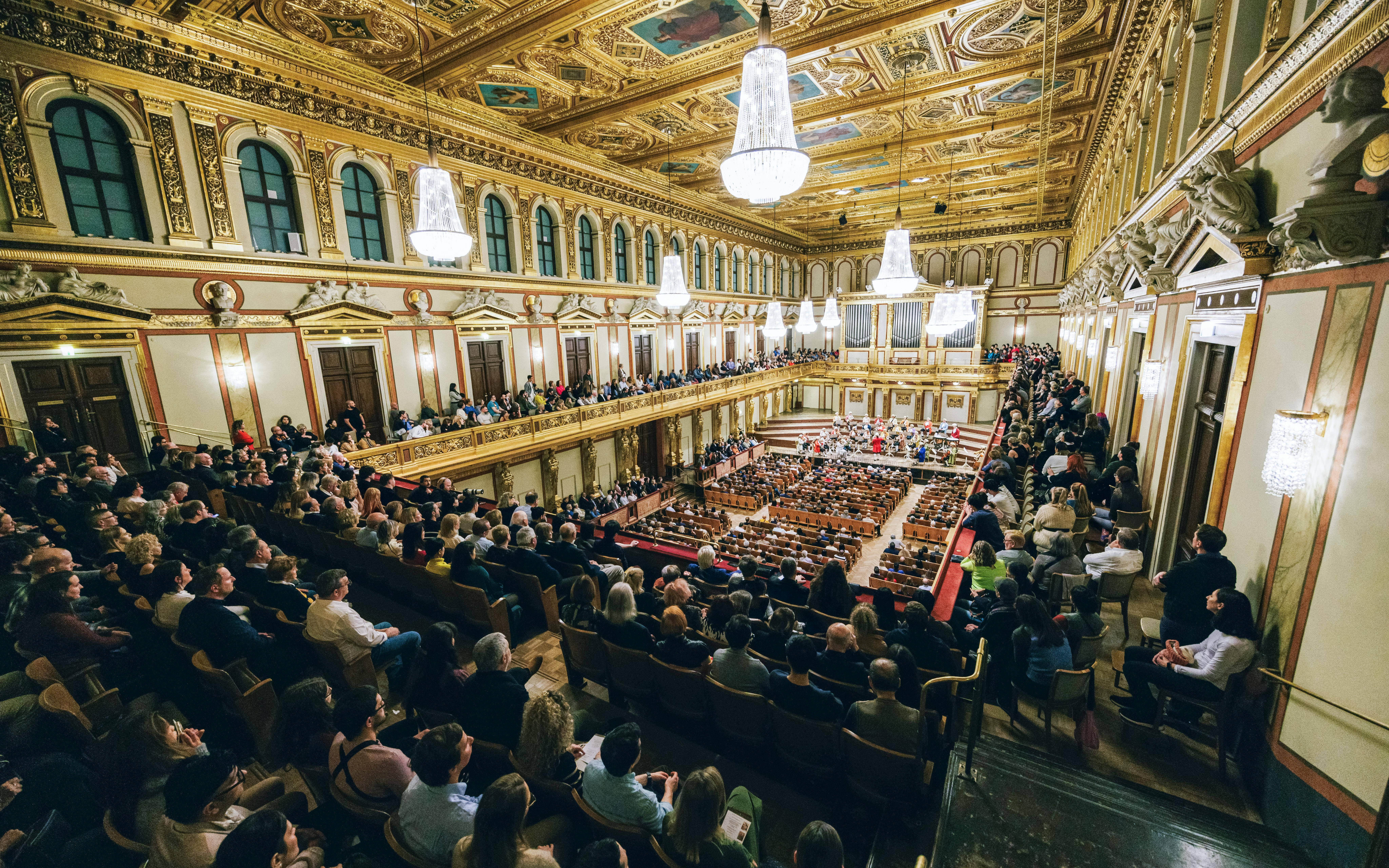 Audience attending a Mozart orchestra concert in an ornate concert hall.