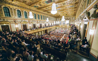 Audience attending a Mozart orchestra concert in an ornate concert hall.