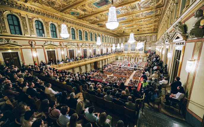 Audience attending a Mozart orchestra concert in an ornate concert hall.