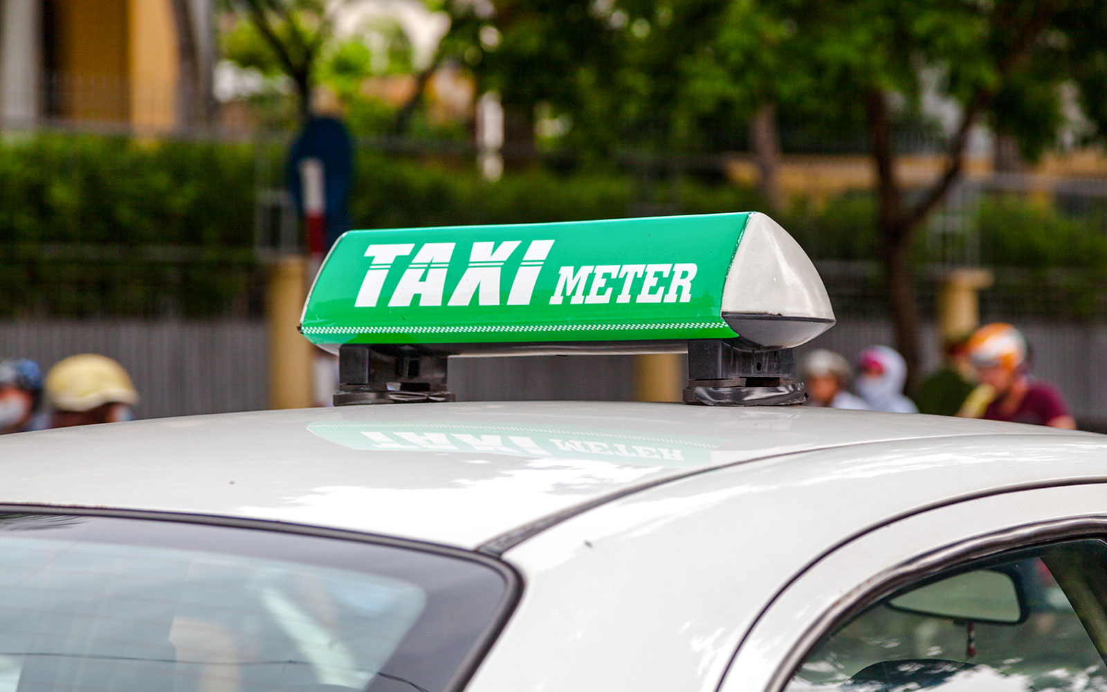 Vietnamese taxi with green taxi meter sign on roof.