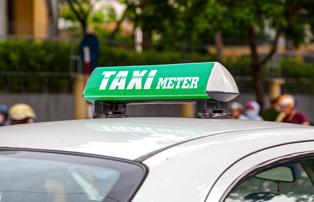 Vietnamese taxi with green taxi meter sign on roof.