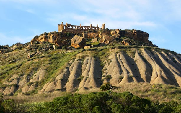 Ancient temple ruins on a hill in Agrigento, Sicily, during sunset.