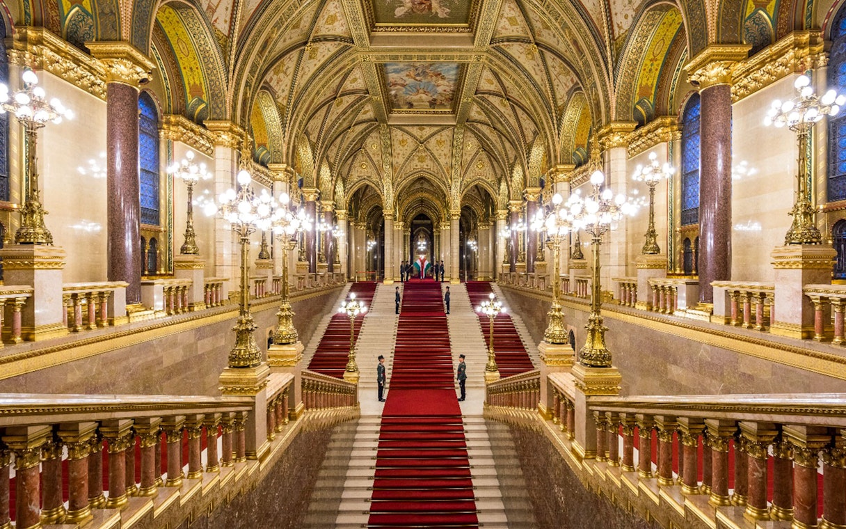 Hungarian Parliament grand staircase with ornate ceiling and red carpet in Budapest.