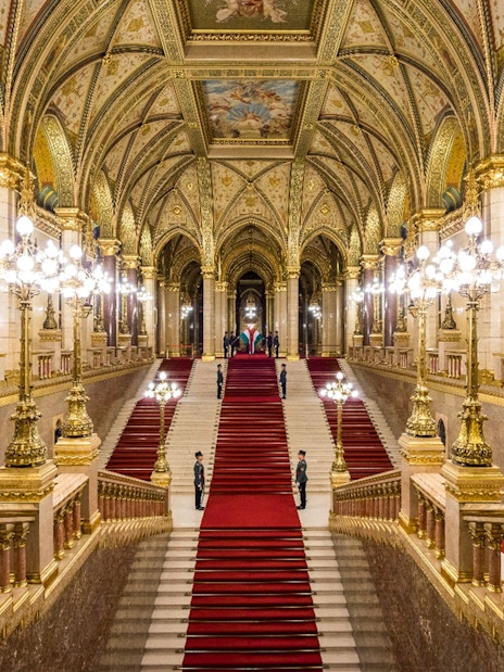 Hungarian Parliament grand staircase with ornate ceiling and red carpet in Budapest.