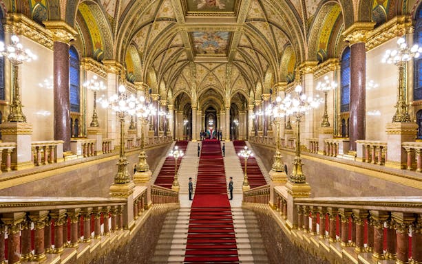 Hungarian Parliament grand staircase with ornate ceiling and red carpet in Budapest.
