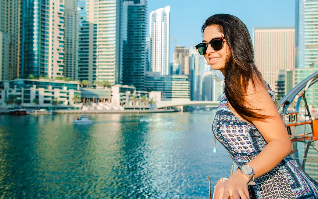 Woman enjoying a dhow cruise in Dubai Marina with skyscrapers in the background.