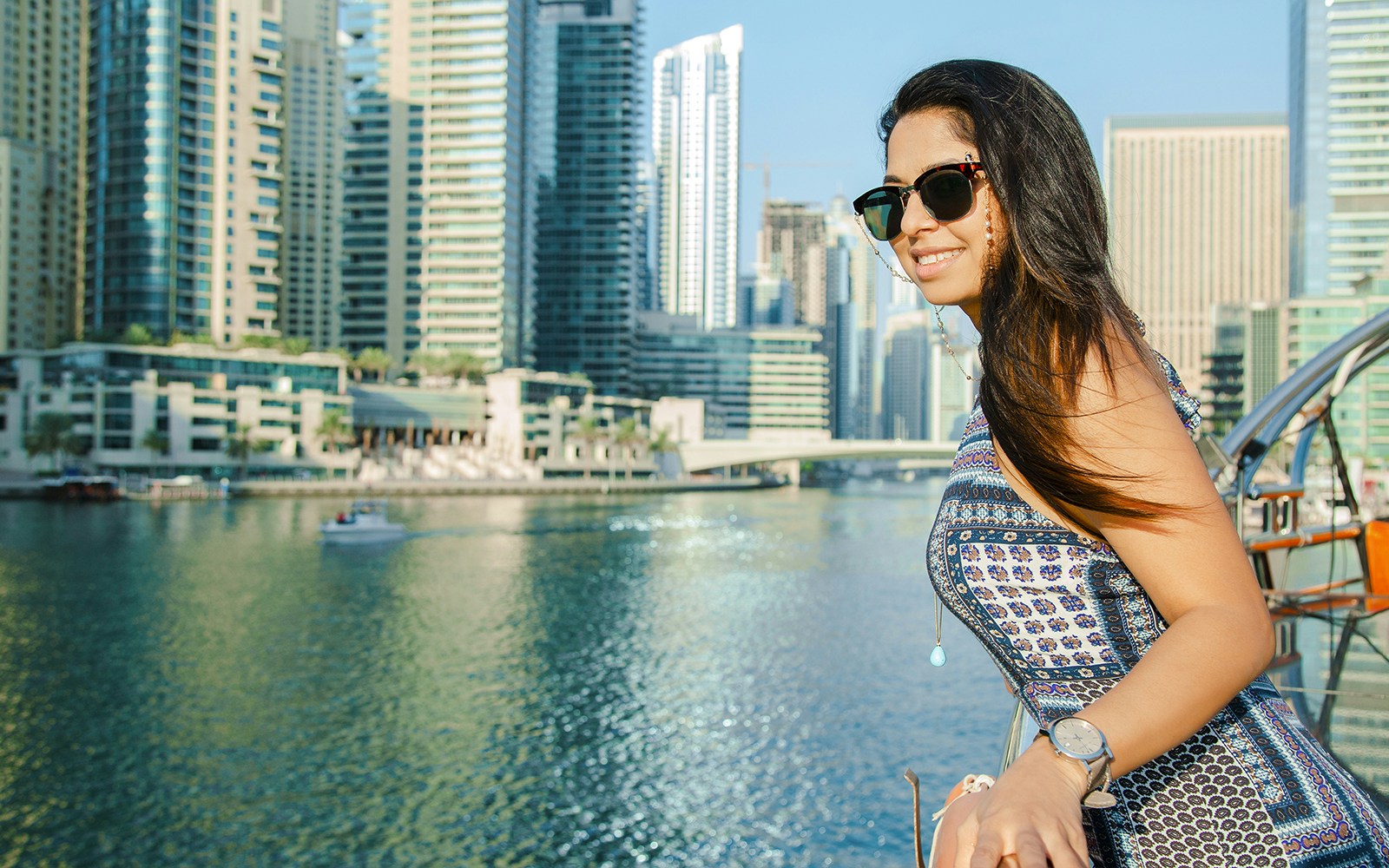 Woman enjoying a sightseeing dhow cruise at Dubai Marina with city skyline in the background.