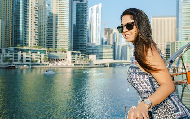Woman enjoying a dhow cruise in Dubai Marina with skyscrapers in the background.