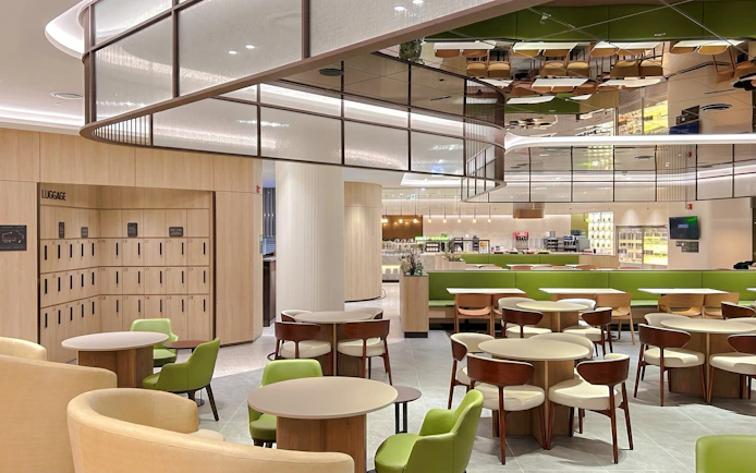 Sky Hub Lounge West seating area with tables, chairs, and luggage lockers.