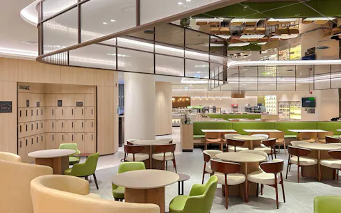 Sky Hub Lounge West seating area with tables, chairs, and luggage lockers.