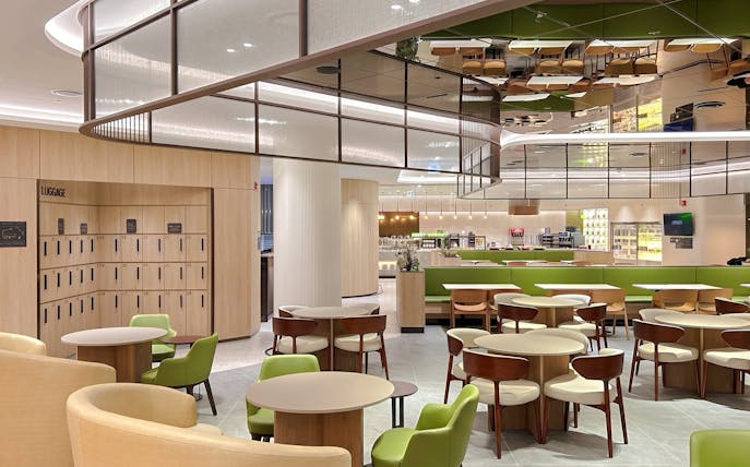 Sky Hub Lounge West seating area with tables, chairs, and luggage lockers.