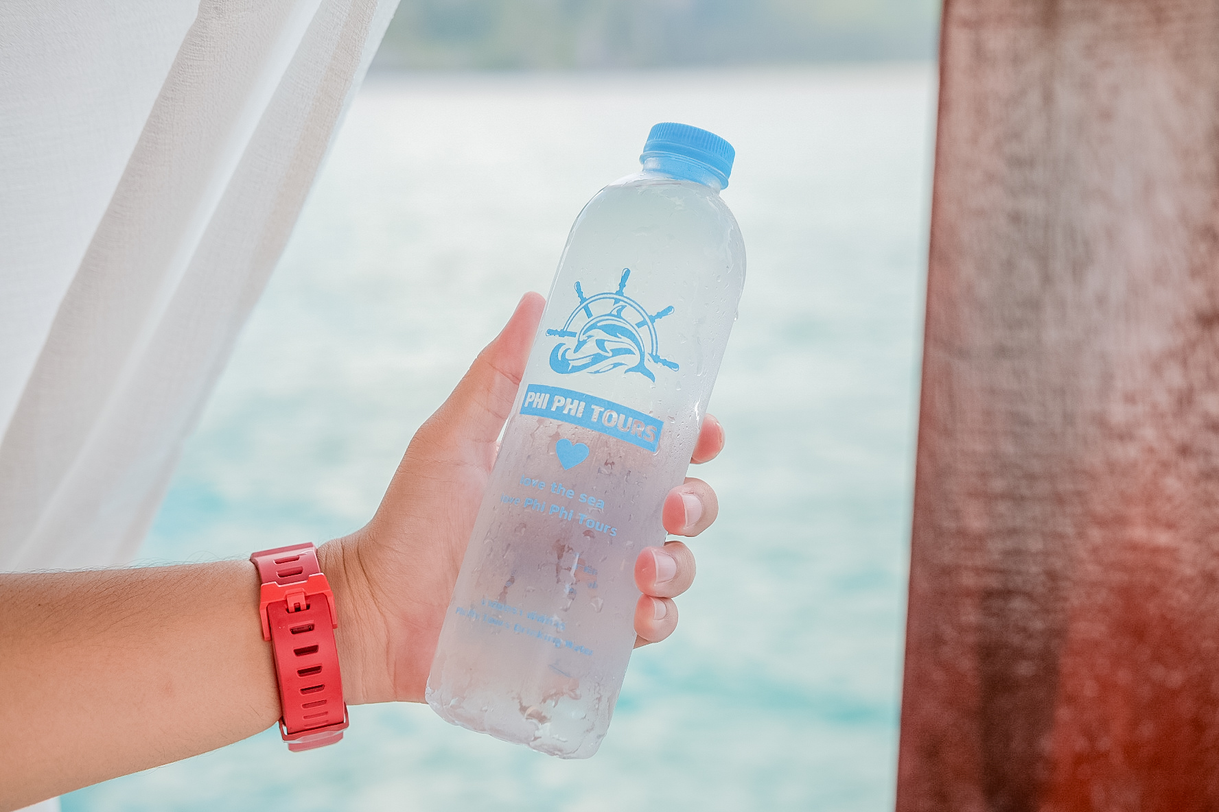 Tourist holding a Phi Phi Tours water bottle on a boat.