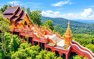 Buddhist temple with ornate architecture surrounded by lush greenery in Lampang, Thailand.