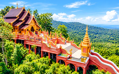 Buddhist temple with ornate architecture surrounded by lush greenery in Lampang, Thailand.