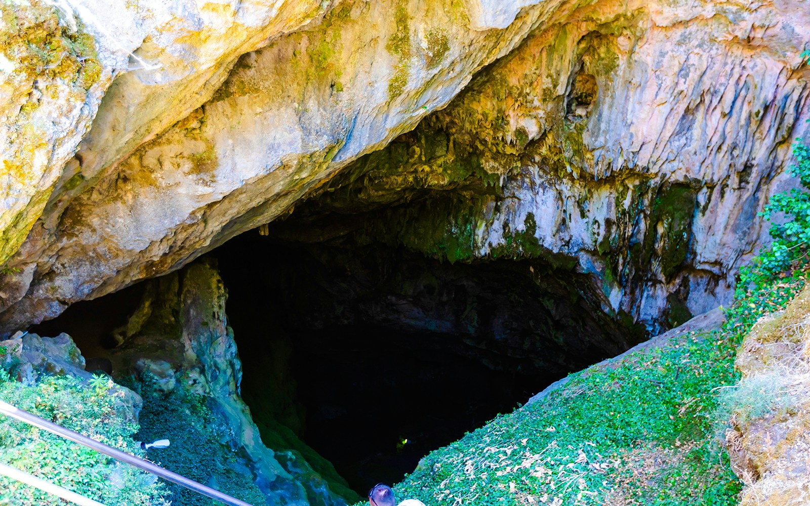Corycian Cave entrance surrounded by rocky formations and greenery in Arachova Village.