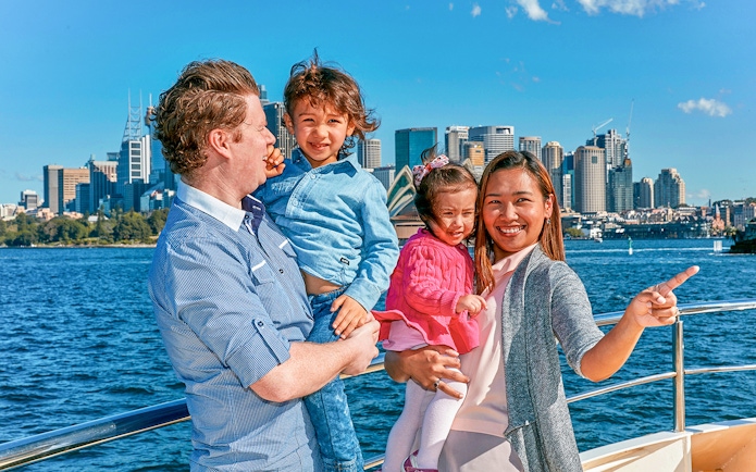Family enjoying Captain Cook Sydney Harbour cruise with city skyline in background.