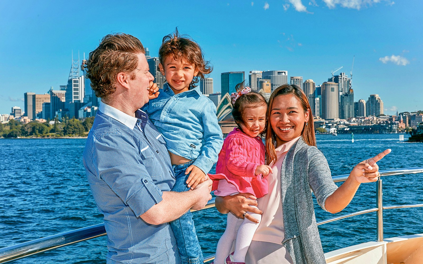 Family enjoying Captain Cook Sydney Harbour cruise with city skyline in background.