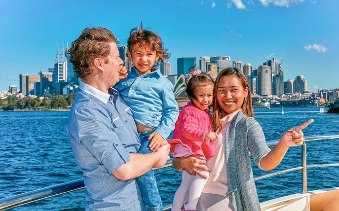 Family enjoying Captain Cook Sydney Harbour cruise with city skyline in background.