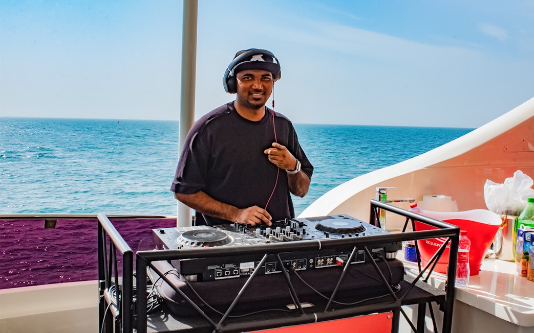 DJ performing on Superyacht TriDeck Cruise with ocean backdrop.