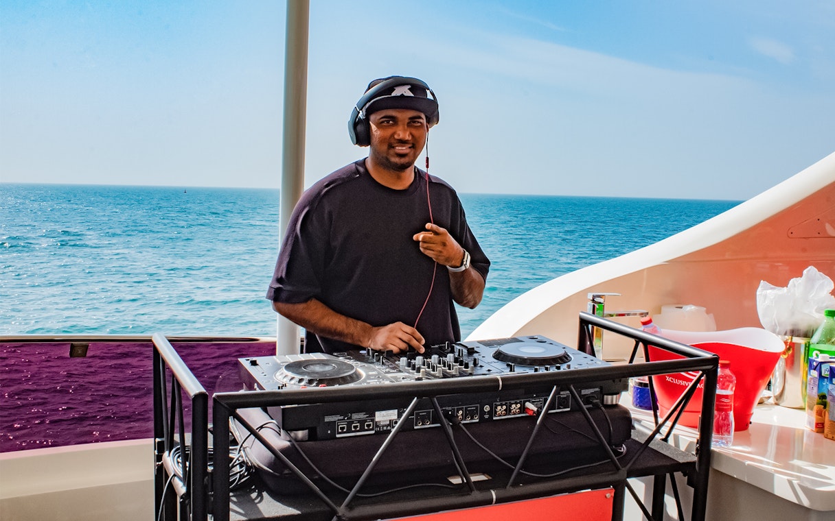 DJ performing on Superyacht TriDeck Cruise with ocean backdrop.