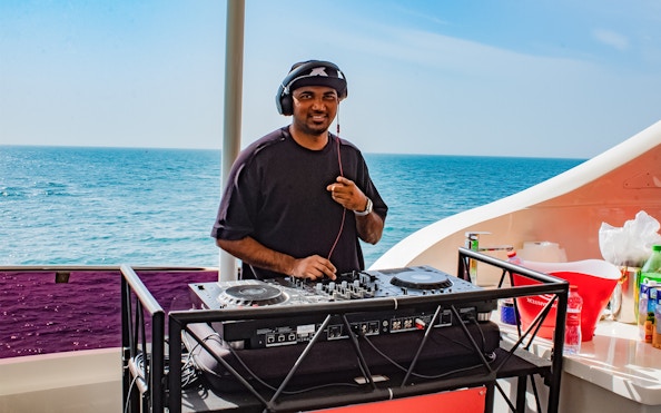 DJ performing on Superyacht TriDeck Cruise with ocean backdrop.