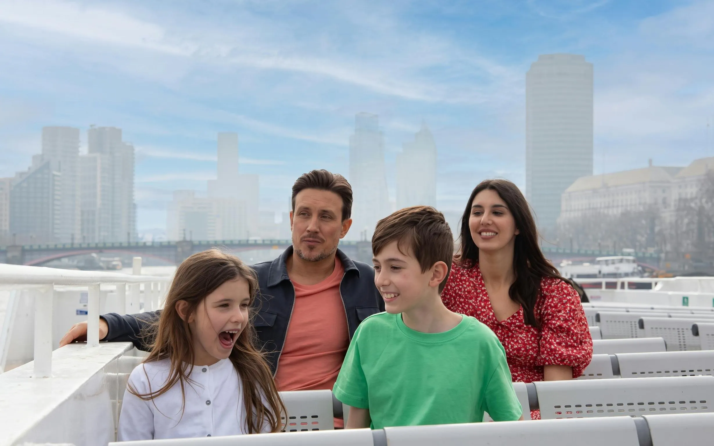 Family enjoying a London city cruise with skyline in the background.