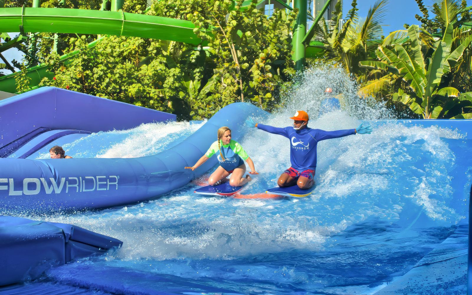 Instructor guiding a girl on a surfboard at Flow Rider, Waterbom Bali water park.
