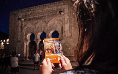 Guided night tour at Medina Azahara with visitors holding a Córdoba map.